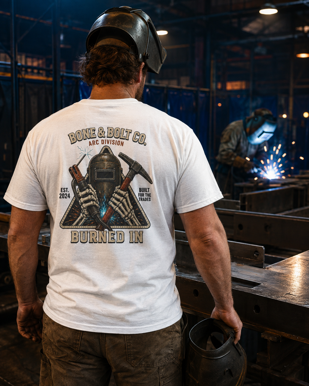 Welder wearing the Arc Division Tee in an industrial fabrication shop