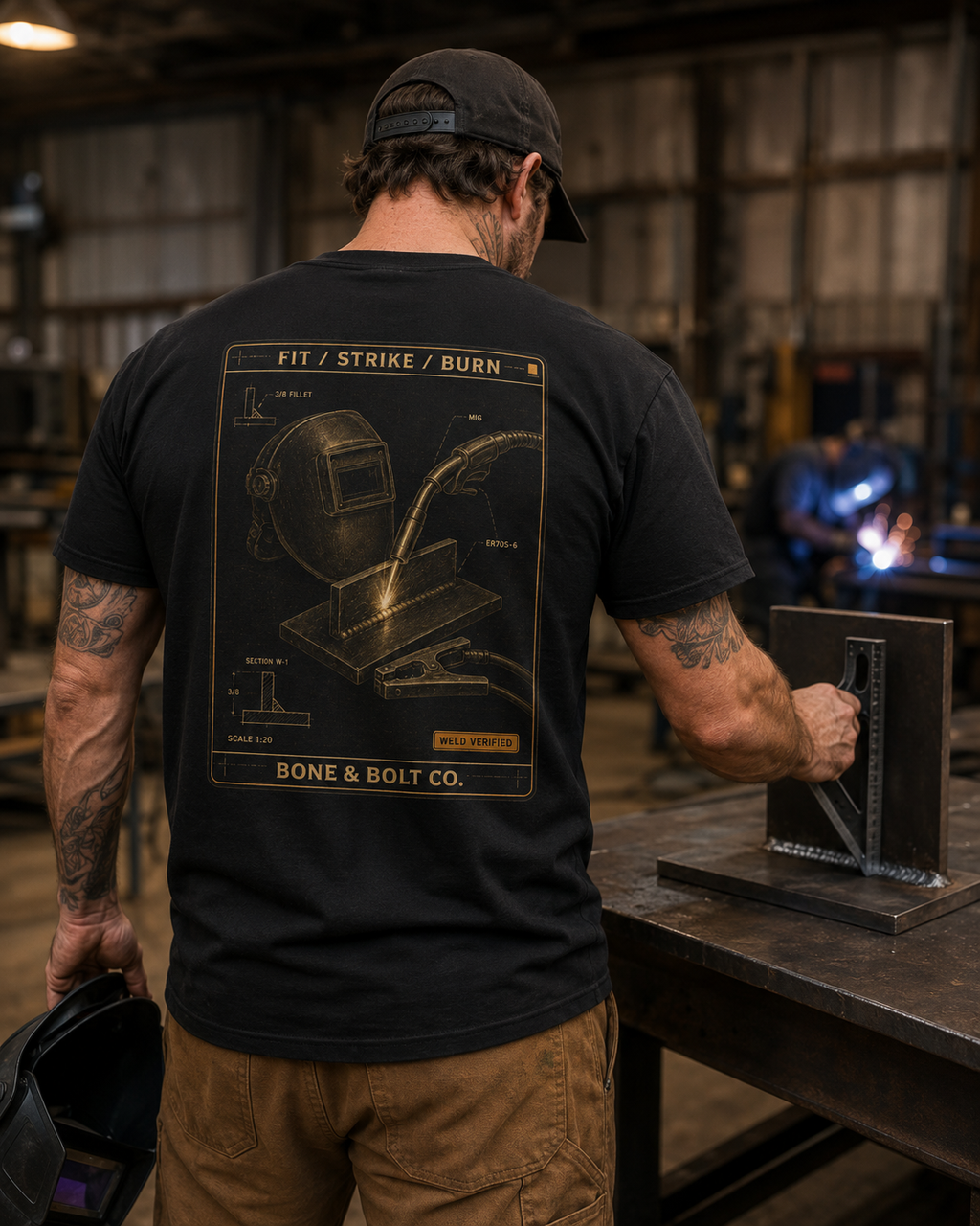 Welder wearing the Fit Strike Burn Tee in an industrial fabrication shop
